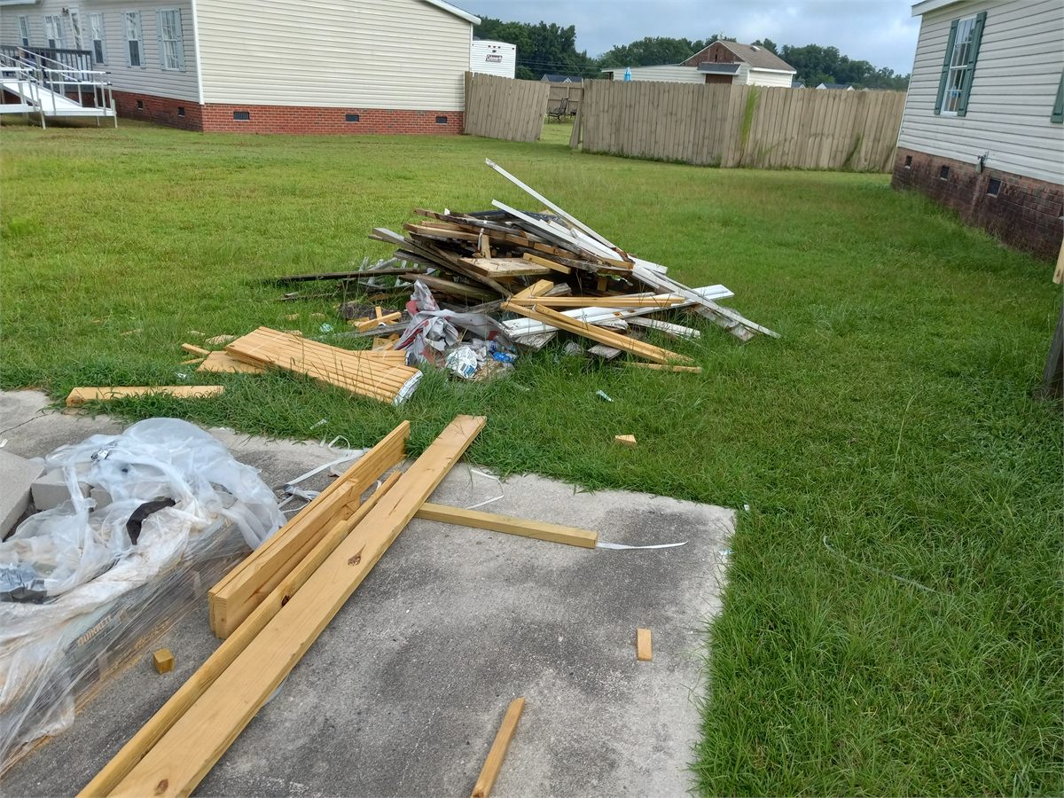 Construction lumber and debris covering a residential yard before cleanup